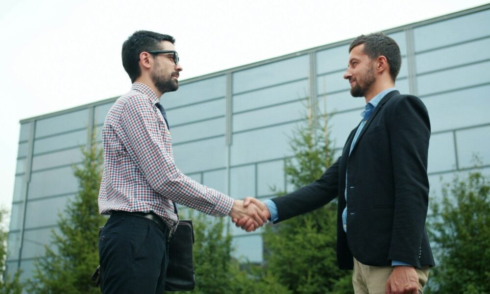 Two businessmen shaking hands outside modern building
