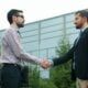 Two businessmen shaking hands outside modern building