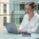 a woman sitting at a table using a laptop computer