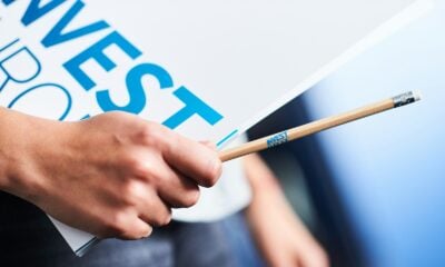 Hand holding "invest" sign and pencil