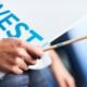 Hand holding "invest" sign and pencil
