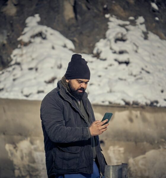 A man with a beard and black beanie using a smartphone outdoors
