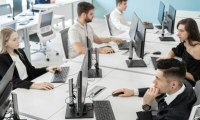 a group of people sitting at a table with computers