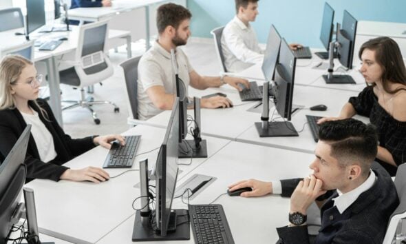 a group of people sitting at a table with computers