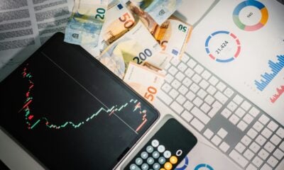 Euro banknotes, a tablet with a stock chart, and financial reports on a desk