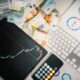 Euro banknotes, a tablet with a stock chart, and financial reports on a desk