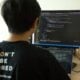 man in black shirt using laptop computer and flat screen monitor