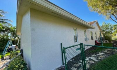 white concrete house with green metal fence