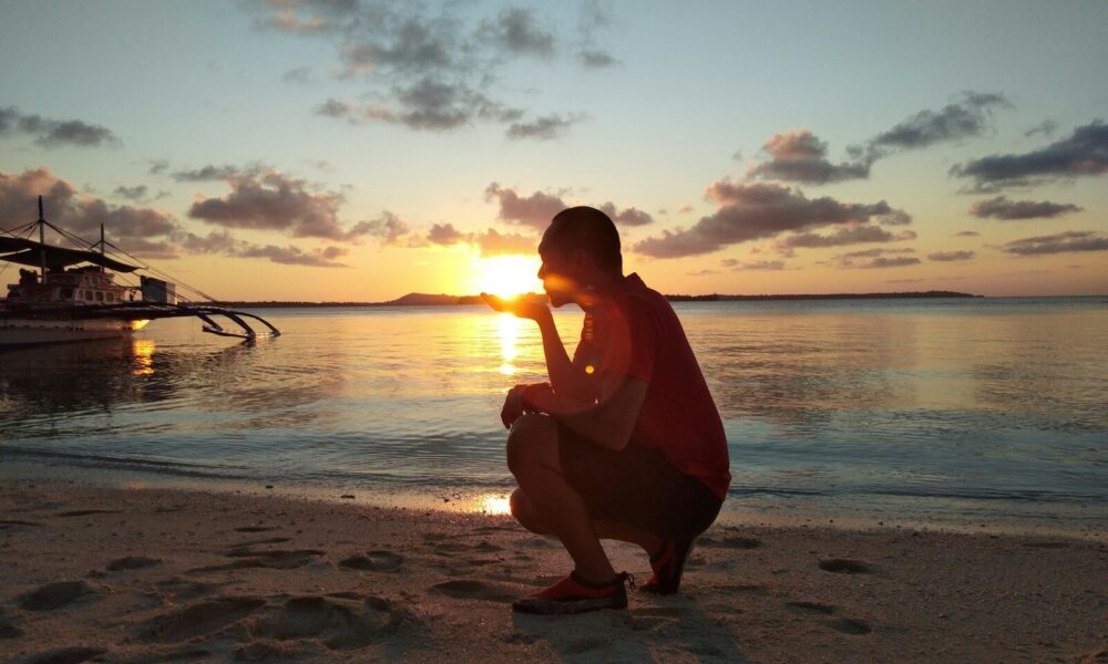 woman in red dress sitting on beach during sunset