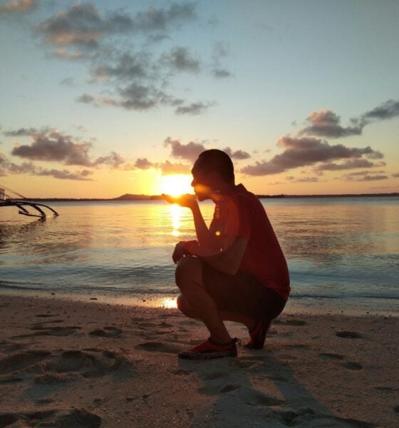 woman in red dress sitting on beach during sunset