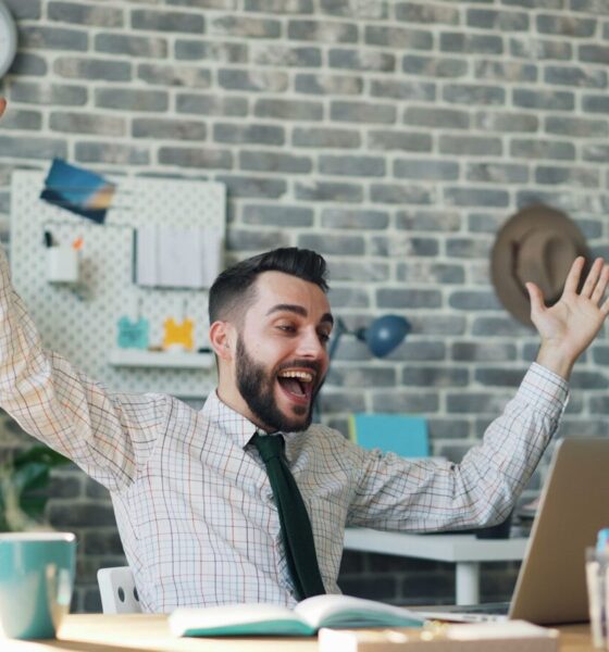 a man sitting at a desk with his arms in the air