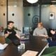 Four people in a meeting around a black table in a modern office