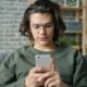 Young man with glasses using a smartphone on couch