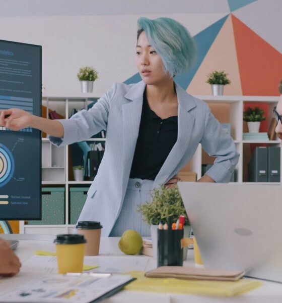 A woman with blue hair pointing at a digital chart during a team meeting