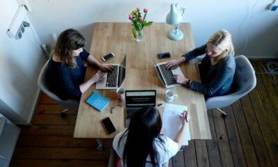 three women sitting around table using laptops