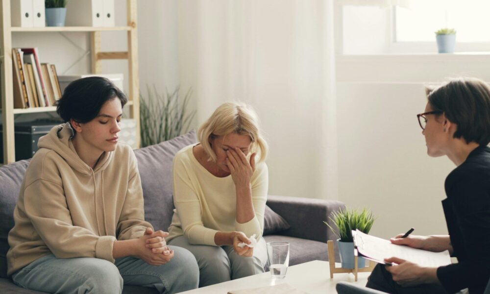 two women sitting on a couch talking to each other