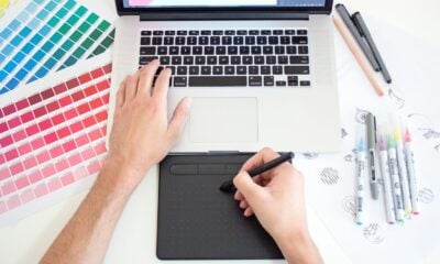 A person using a digital drawing tablet and laptop with color swatches and markers