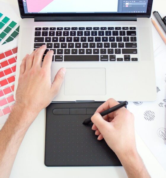 A person using a digital drawing tablet and laptop with color swatches and markers