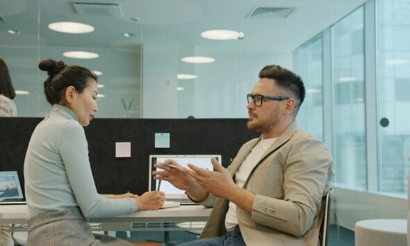 Two colleagues discussing work in a modern office