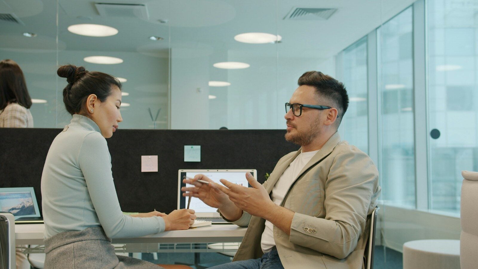 Two colleagues discussing work in a modern office