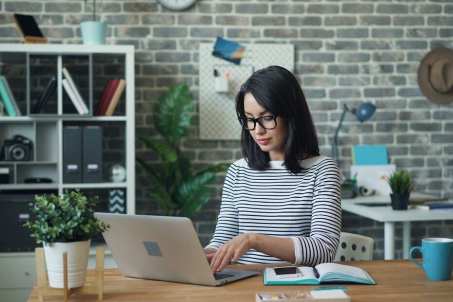 a woman sitting at a table using a laptop computer