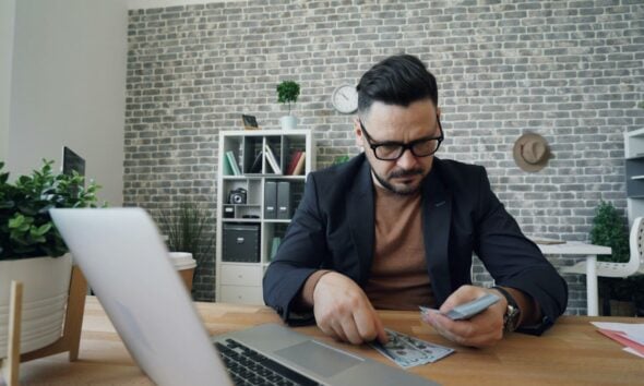a man sitting at a table in front of a laptop