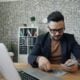 a man sitting at a table in front of a laptop