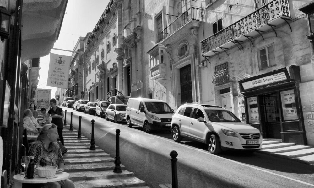 grayscale photo of cars parked on sidewalk