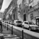 grayscale photo of cars parked on sidewalk