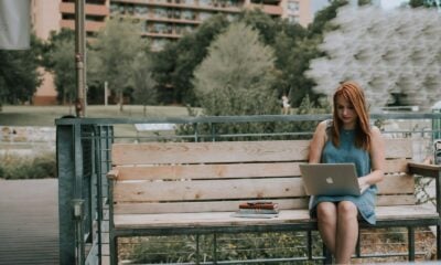 woman sitting on bench white using MacBook Pro