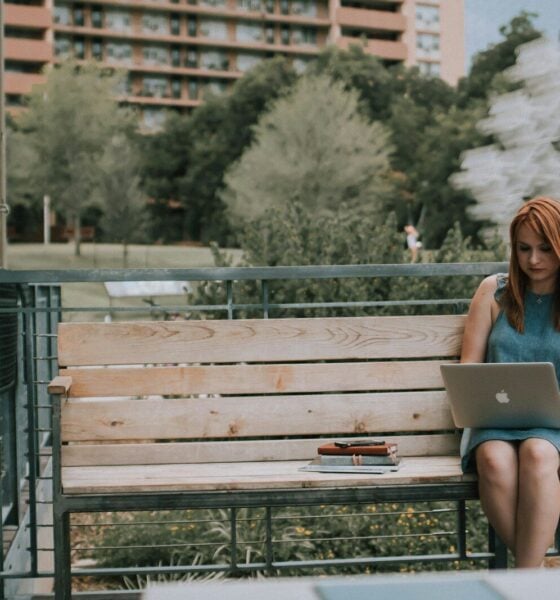 woman sitting on bench white using MacBook Pro
