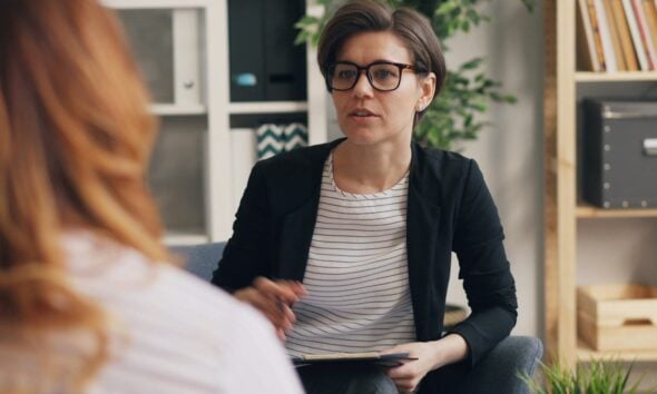 a woman sitting on a couch talking to another woman