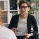 a woman sitting on a couch talking to another woman