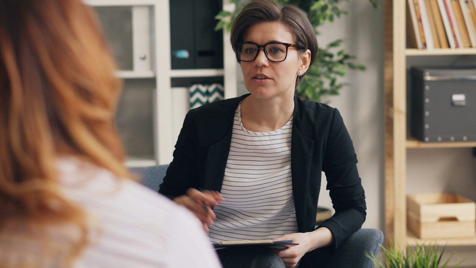 a woman sitting on a couch talking to another woman