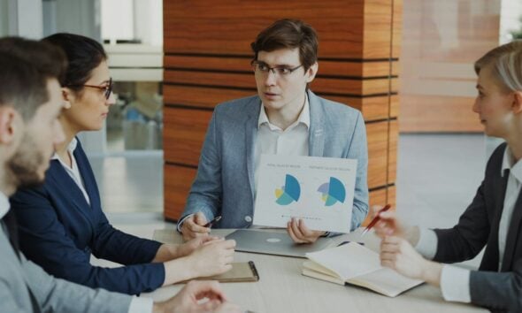 Man presenting charts to colleagues in a meeting