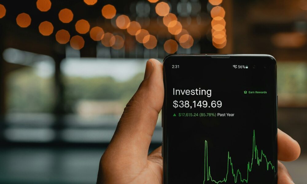 a person holding up a cell phone with a stock chart on it
