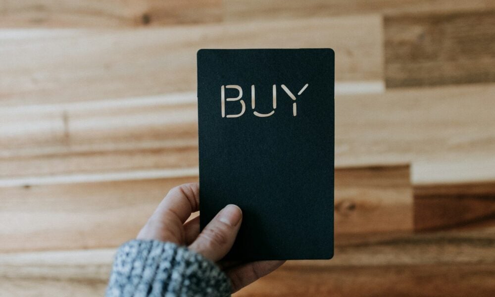 a person holding a black book with the word buy written on it