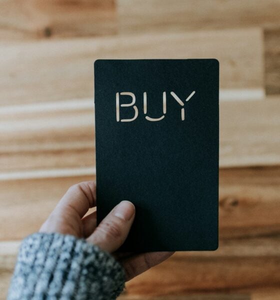 a person holding a black book with the word buy written on it