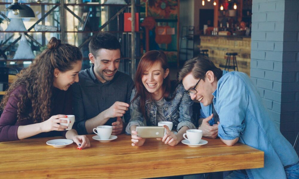 Friends watch a phone in a coffee shop
