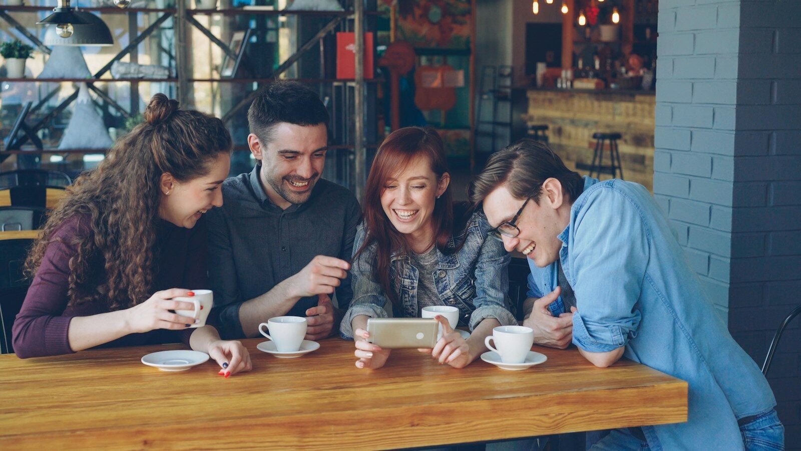 Friends watch a phone in a coffee shop