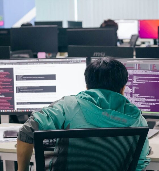 a man sitting in front of two computer monitors