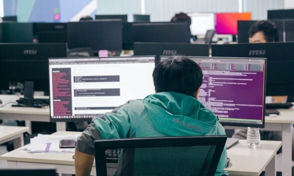 a man sitting in front of two computer monitors